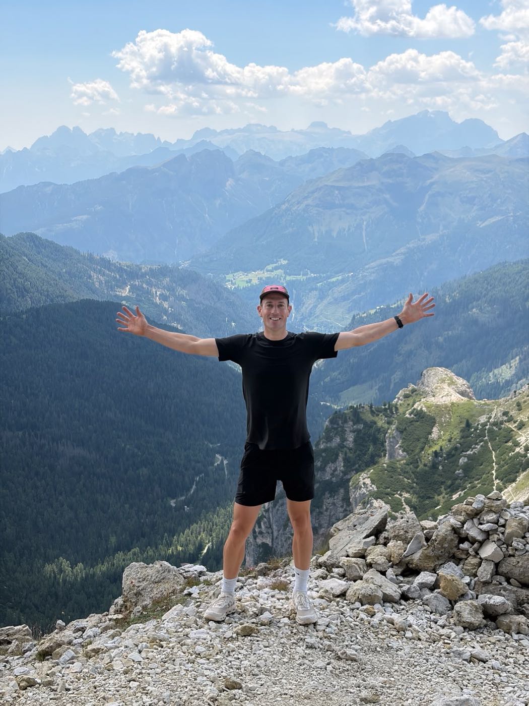 Neil Sampson on a mountain ridge, arms outstretched